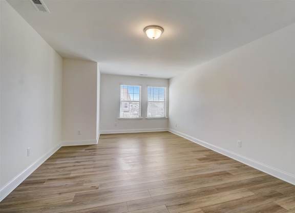 a bedroom with hardwood floors and a large window
