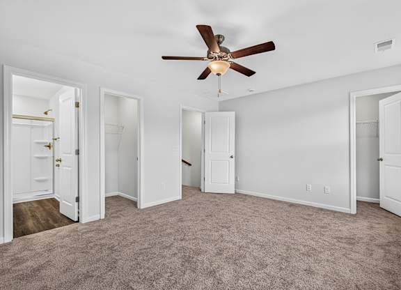 A room with a ceiling fan and carpeted floor.