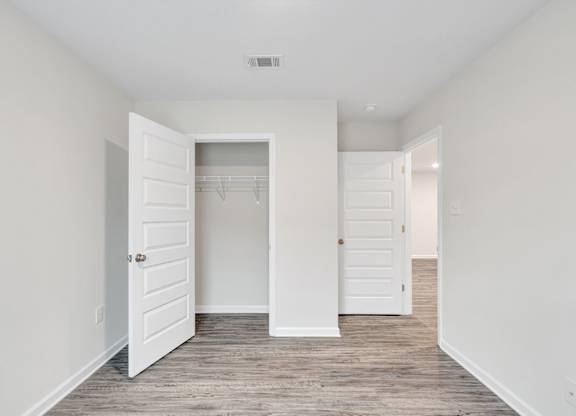 A white door is open to a room with a wooden floor.