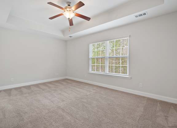 Harris Trail Luxury Townhomes for rent Richmond Hill, GA photo of an empty living room with a ceiling fan and a window