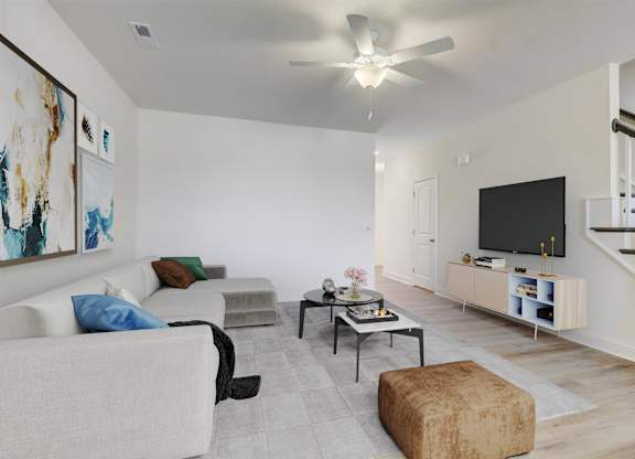 A living room with a couch, chair, ottoman, and a television.