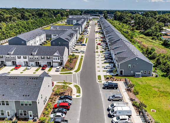 A long row of houses with cars parked in front.