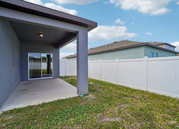 A grey house with a white fence in the background.