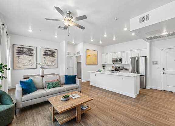 A modern living room with a white ceiling fan and a wooden coffee table.