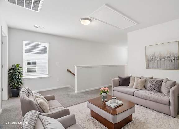 A living room with a grey couch, a coffee table, and a painting on the wall.