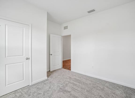 A room with a white door and a carpeted floor.