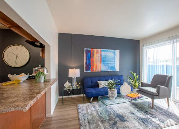 Living room with large sliding windows at Midtown on Seneca, a pet-friendly apartment community near East Central Tucson, Tucson, AZ.