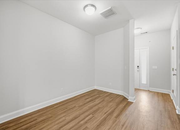 A room with wooden flooring and white walls.