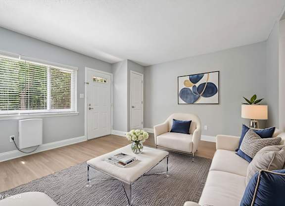 A living room with a white couch, a grey coffee table, and a painting on the wall.