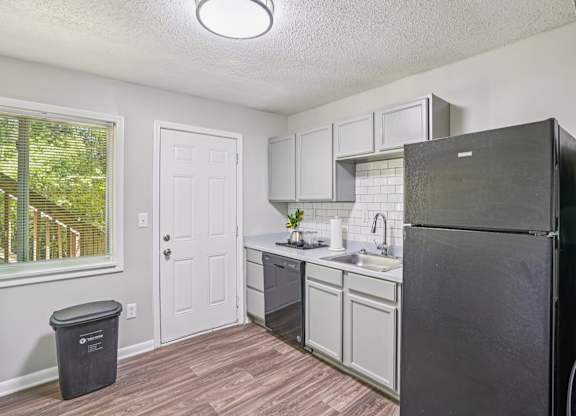 A kitchen with a black refrigerator and white cabinets.