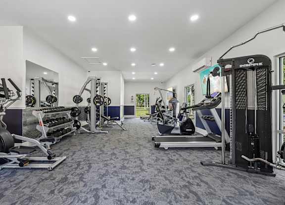 A spacious gym with a variety of equipment including treadmills, weight machines, and free weights.