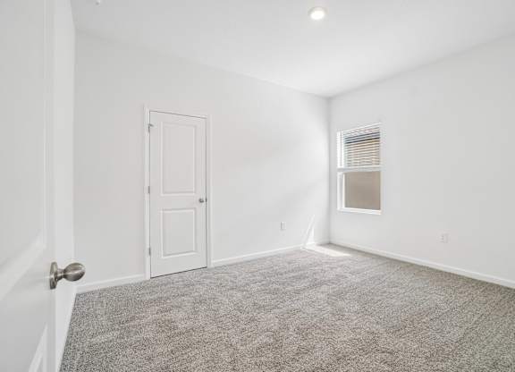 A room with a carpeted floor and a door.