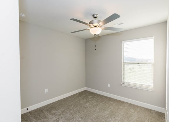 an empty room with a ceiling fan and a window