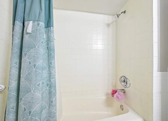 A shower with a blue curtain and a pink flower.