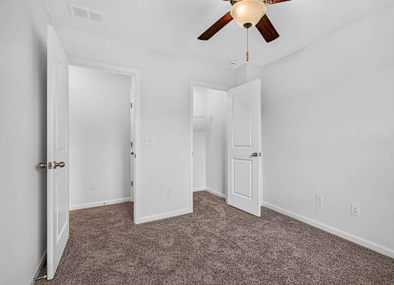 A room with a ceiling fan and carpeted floor.