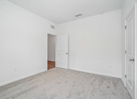 A room with a carpeted floor and two white doors.