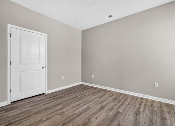 A room with a white door and wooden flooring.