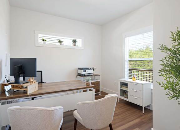 A room with a desk, chairs, and a printer.