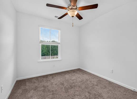 A room with a ceiling fan and carpeted floor.