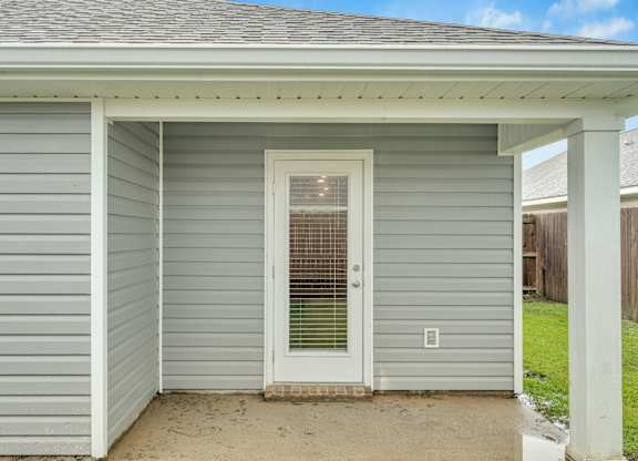 A small house with a grey siding and a white door.