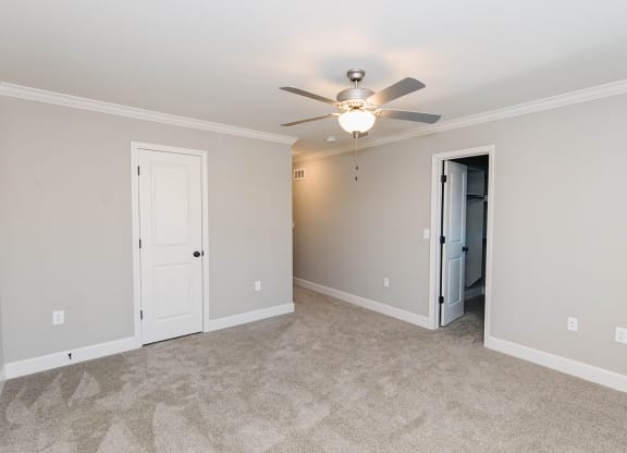 a living room with a ceiling fan and a large room with walls and doors