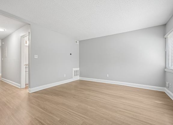 A room with wooden flooring and white walls.