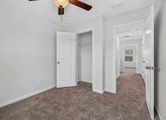 A room with a carpeted floor and a ceiling fan.