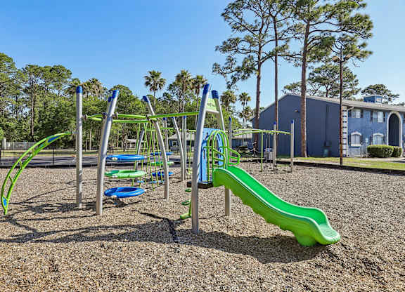 A playground with a green slide and a blue and green climbing frame.