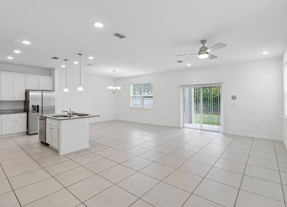 A spacious kitchen and living room with white tile flooring and ceiling.