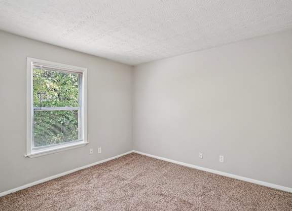 A room with a window and carpeted floor.