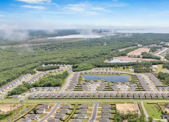 A bird's eye view of a residential area with a lake in the middle.