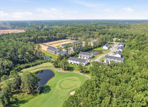 A bird's eye view of a golf course surrounded by trees.