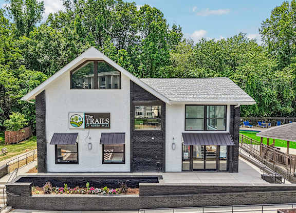 A white building with a black roof and a green sign that says