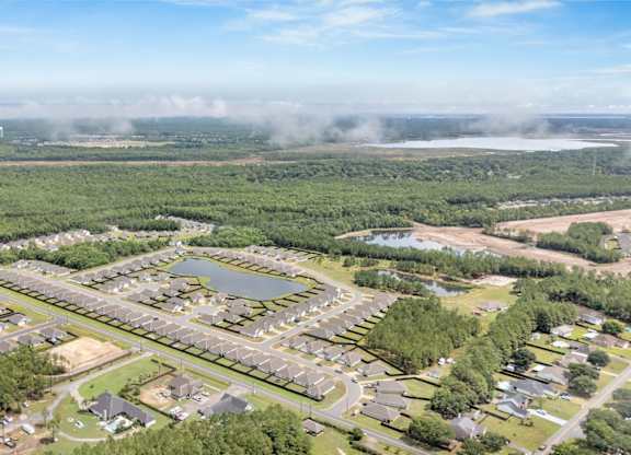 A bird's eye view of a residential area with houses, roads, and a lake.