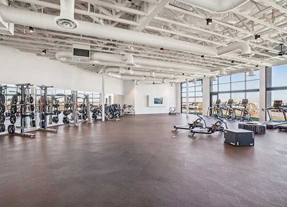 A spacious gym with a variety of equipment and a large mirror on the wall.