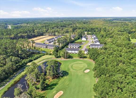 A golf course with a clubhouse and several houses in the background.