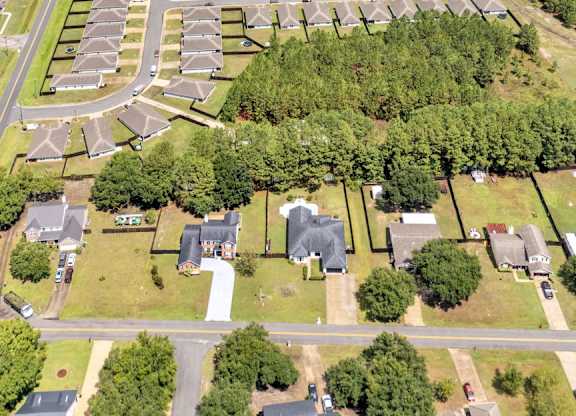 A bird's eye view of a residential area with houses, roads, and a lake.