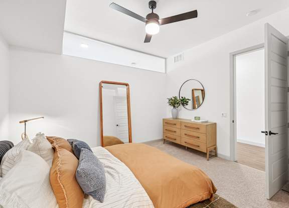 A bedroom with a bed, dresser, mirror, and a ceiling fan.