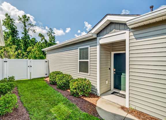 A house with a green lawn and a white fence.