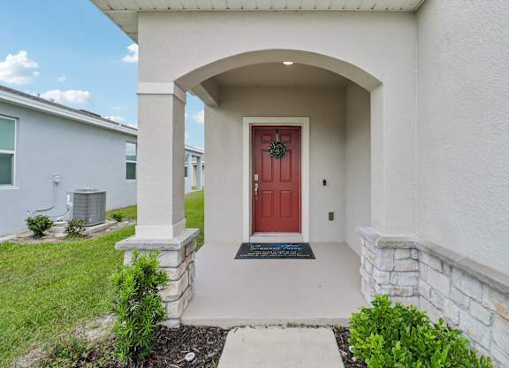 A house with a red door and a stone pillar.