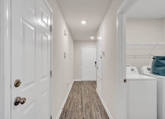 A hallway with white doors and a wooden floor.