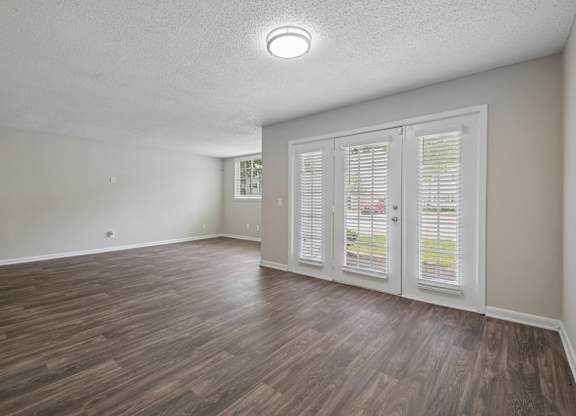 A room with wooden flooring and a window with white shutters.
