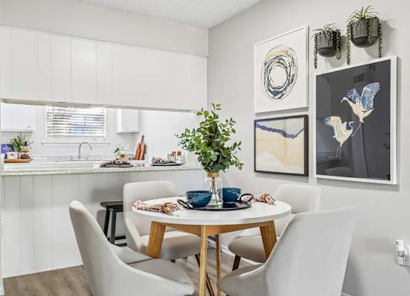 A dining room with a table set for two and a potted plant on the table.