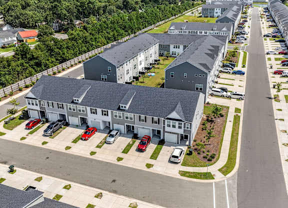A long row of houses with cars parked in front.