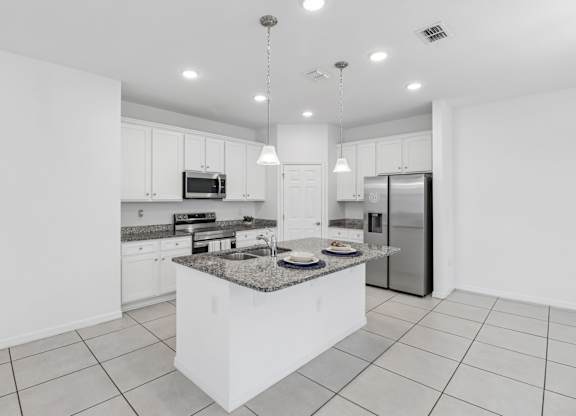A modern kitchen with a granite countertop and stainless steel appliances.