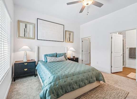 A bedroom with a bed, two lamps, and a ceiling fan.