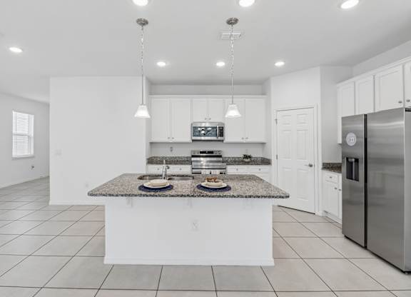 A modern kitchen with a granite countertop and stainless steel appliances.