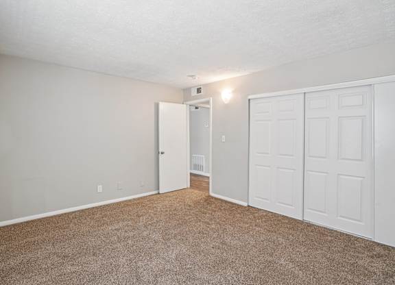 A room with a white door and a brown carpet.