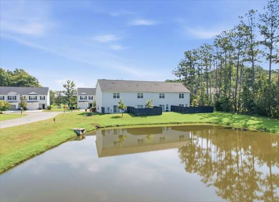 A serene landscape with a house, trees, and a pond.