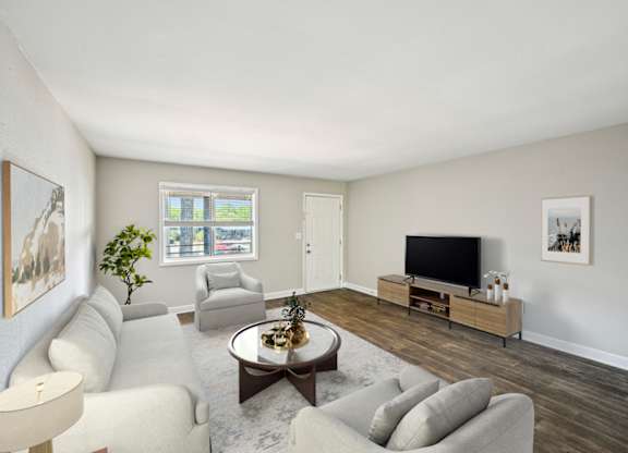 Living room with gray furniture, dark wood floors, and a television.